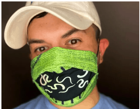 Guest sporting a white cap and a vibrant green-and-black Oogie Boogie face mask from The Nightmare Before Christmas, smiling for the camera.