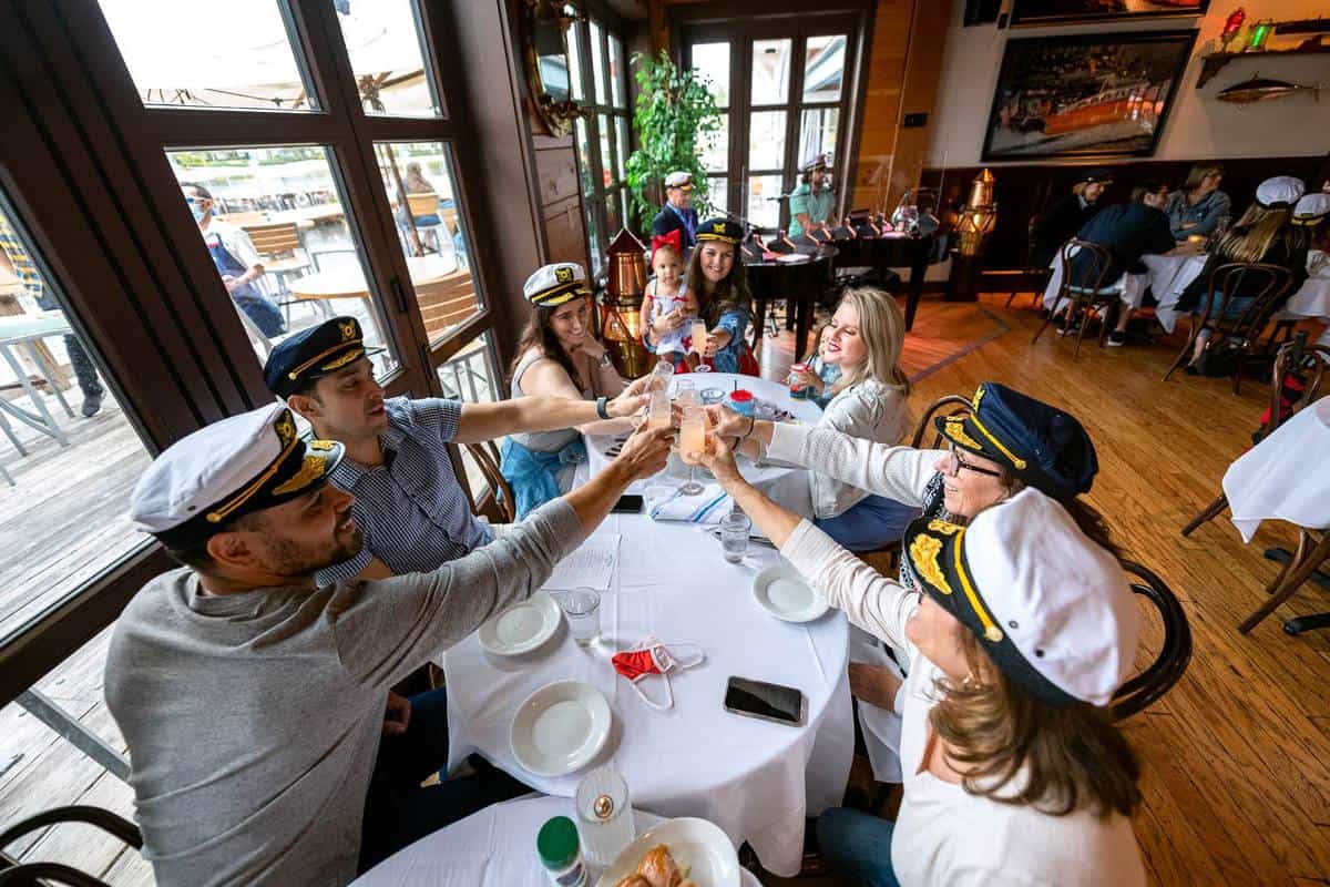Guests in captain hats raise their glasses together at The Boathouse’s vibrant Captains Sing Along Brunch in Disney Springs, joining the fun with lively music and cheerful group energy.