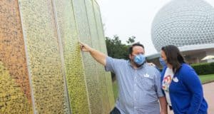 Guests wearing masks admire the Leave a Legacy panels near Spaceship Earth at Epcot, highlighting the refreshed entrance area of the park.
