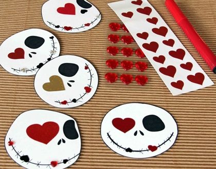 Five Jack Skellington-inspired skull crafts decorated with hearts and stickers, accompanied by a red marker on a rustic table, channel the spooky-sweet spirit of Halloween Town for the ultimate Disney-themed Valentine’s Day activity.