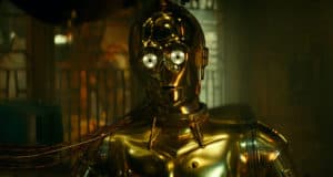 C-3PO stands in a dimly lit attraction space, golden plating gleaming and colorful wires visible, ready to thrill Star Wars fans with heroic adventures.