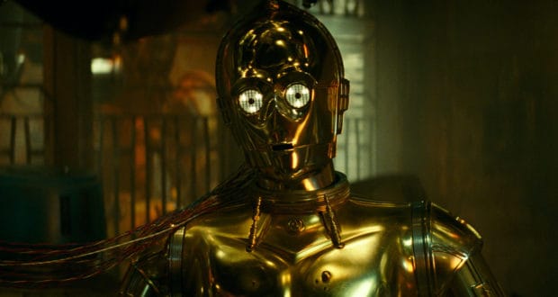 C-3PO stands in a dimly lit attraction space, golden plating gleaming and colorful wires visible, ready to thrill Star Wars fans with heroic adventures.
