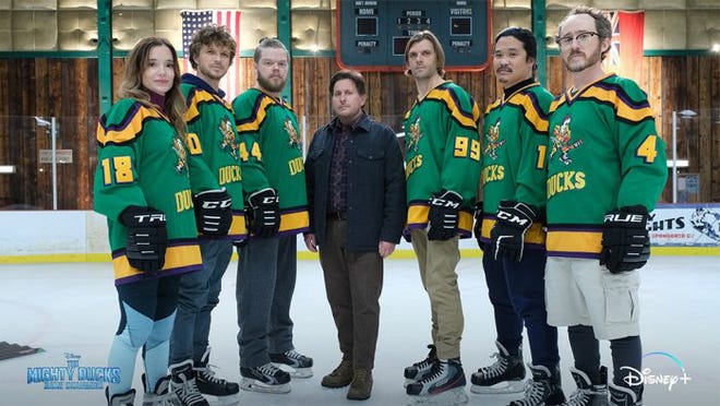 Members of The Mighty Ducks, dressed in their iconic green jerseys, join Coach Bombay on the ice for a photo op. Channeling the Game Changers energy, this Disney+ moment invites fans to relive the legendary hockey adventures right from the rink.