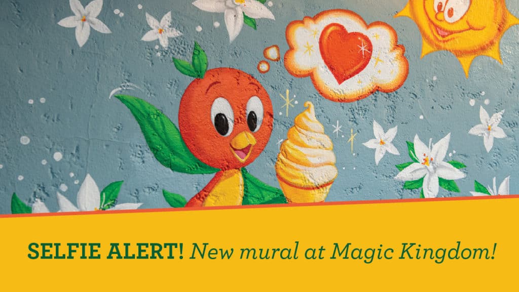 Orange Bird enjoys an ice cream treat beneath a sunny sky, surrounded by cheerful flowers and hearts on the vibrant New Mural wall at Magic Kingdom.