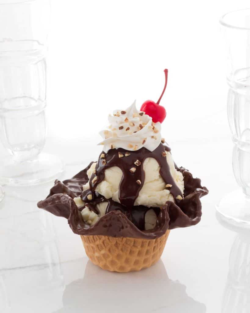 A magical Disney Springs treat featuring vanilla ice cream served in a chocolate waffle bowl, piled high with whipped cream, crunchy nuts, rich chocolate sauce, and a cherry on top—plus two adorable Ghirardelli Mini Caramel Bunnies for that extra Disney flair.