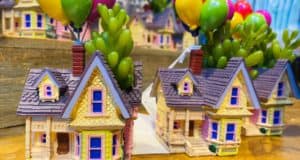 Two whimsical miniature houses, each topped with vibrant Up-inspired balloons and lush green plants sprouting from their chimneys, rest on a wooden display—just the kind of magical discovery you’d expect to find at Disney Springs’ Up Finds.