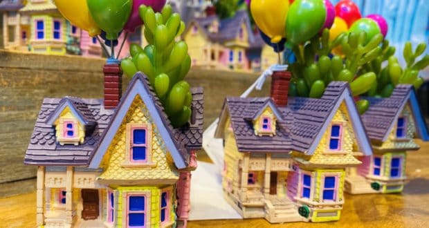Two whimsical miniature houses, each topped with vibrant Up-inspired balloons and lush green plants sprouting from their chimneys, rest on a wooden display—just the kind of magical discovery you’d expect to find at Disney Springs’ Up Finds.