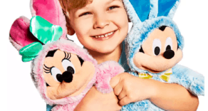 A happy guest embraces the pink Minnie and blue Mickey Easter Bunny plush characters, both dressed in adorable bunny costumes, perfect for Disney fans and available at shopDisney.