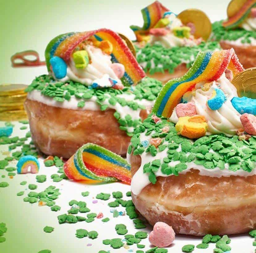 Everglazed’s Shamrock Supreme Donut at Disney Springs channels festive theme park vibes with bright green sprinkles, a generous swirl of whipped cream, colorful rainbow candy, and shiny gold chocolate coins crowning the glazed donuts—a whimsical treat perfect for your day of Disney adventure.