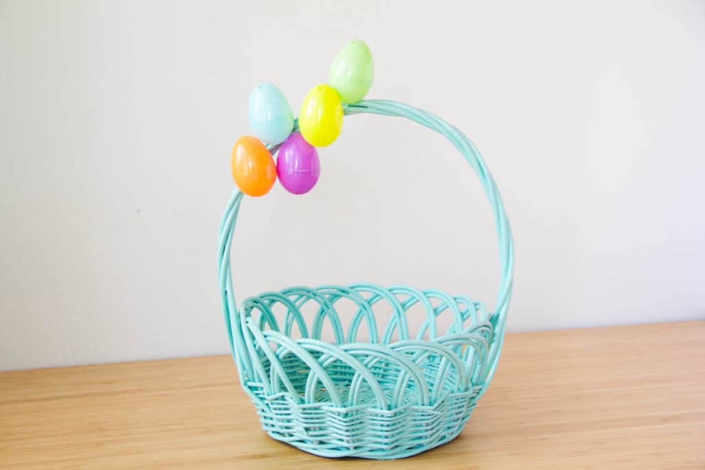 A turquoise wicker Easter basket inspired by Pixar’s Up, decorated with colorful plastic eggs on the handle, is displayed on a wooden table—perfect for fans at Disney’s Hollywood Studios or for recreating that magical movie moment at home.
