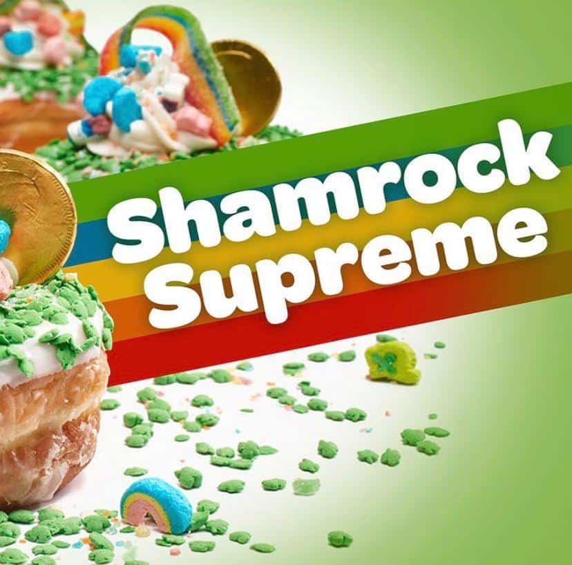 Celebrate St. Patrick’s Day at Disney Springs with festive green donuts from Everglazed, topped with shimmering gold coins and marshmallows, and bold "Shamrock Supreme" lettering set against a lively striped backdrop—capturing the ultimate Shamrock Supreme Donut experience in true Disney style.