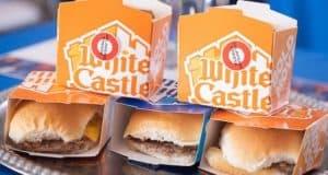 Four White Castle sliders served on a tray, with two signature orange and white boxes behind them—a delicious preview for foodies gearing up for White Castle’s grand opening next week at Walt Disney World.
