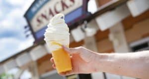 A tempting swirl of vanilla soft serve crowns a bright Vanilla Orange Slushy Float, ready to enjoy in the lively atmosphere of Disney Springs.