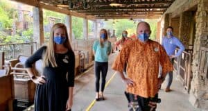 Cast Members in Disney uniforms, all wearing masks, stand spaced out on the empty Expedition Everest loading platform at Disney's Animal Kingdom, celebrating the 15th anniversary of this legendary thrill ride.