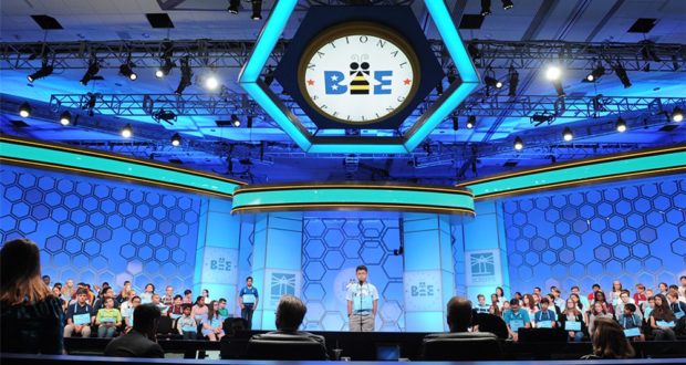 A finalist takes center stage at the Scripps National Spelling Bee, captivating an eager crowd and attentive panel of judges in the grand event hall.