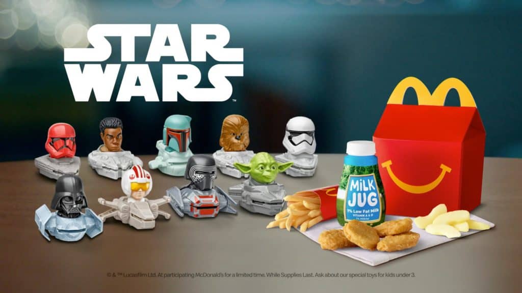 At a lively theme park, a McDonald's Happy Meal tray tempts guests with crispy chicken nuggets, golden fries, a milk jug, and limited-edition Star Wars toys—an irresistible combo for fans eager to collect galactic memorabilia between thrilling rides and immersive attractions.