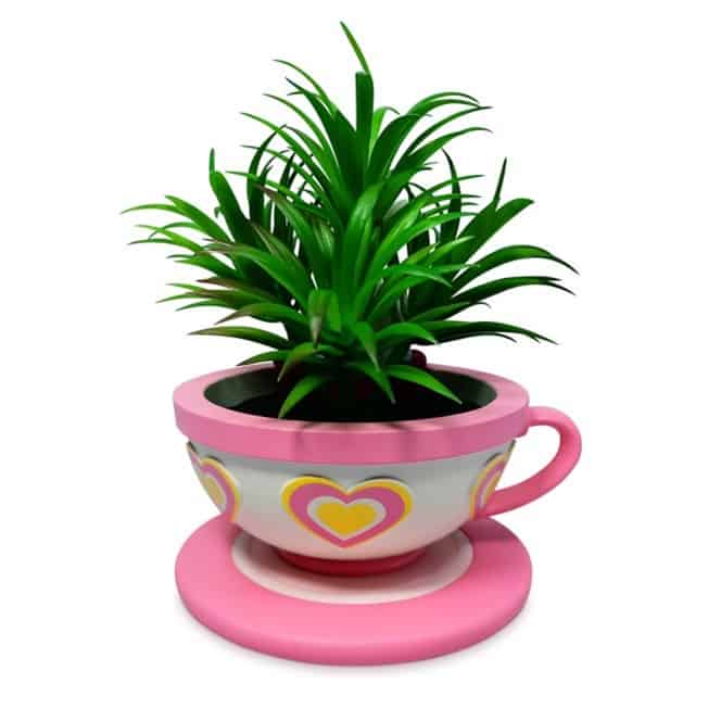 Whimsical green plant in a pink teacup planter with heart accents, set on a matching saucer—reminiscent of Alice’s Mad Tea Party at Disneyland, bringing playful theme park magic to your space.