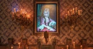 A luminous portrait of a woman glows between two elaborate candle sconces on a richly patterned wall, capturing the enchanting, ghostly vibes of Disneyland’s iconic Haunted Mansion attraction.