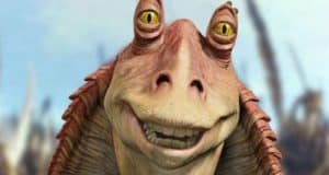 A close-up of Jar Jar Binks, the animated Star Wars alien with big yellow eyes and pinkish skin, smiling warmly as he greets guests at a Star Wars-themed attraction.