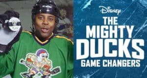 Kenan Thompson in a classic green Mighty Ducks hockey jersey holds a puck, standing next to "The Mighty Ducks: Game Changers" Disney logo, capturing the nostalgic energy of the beloved franchise for Disney fans.