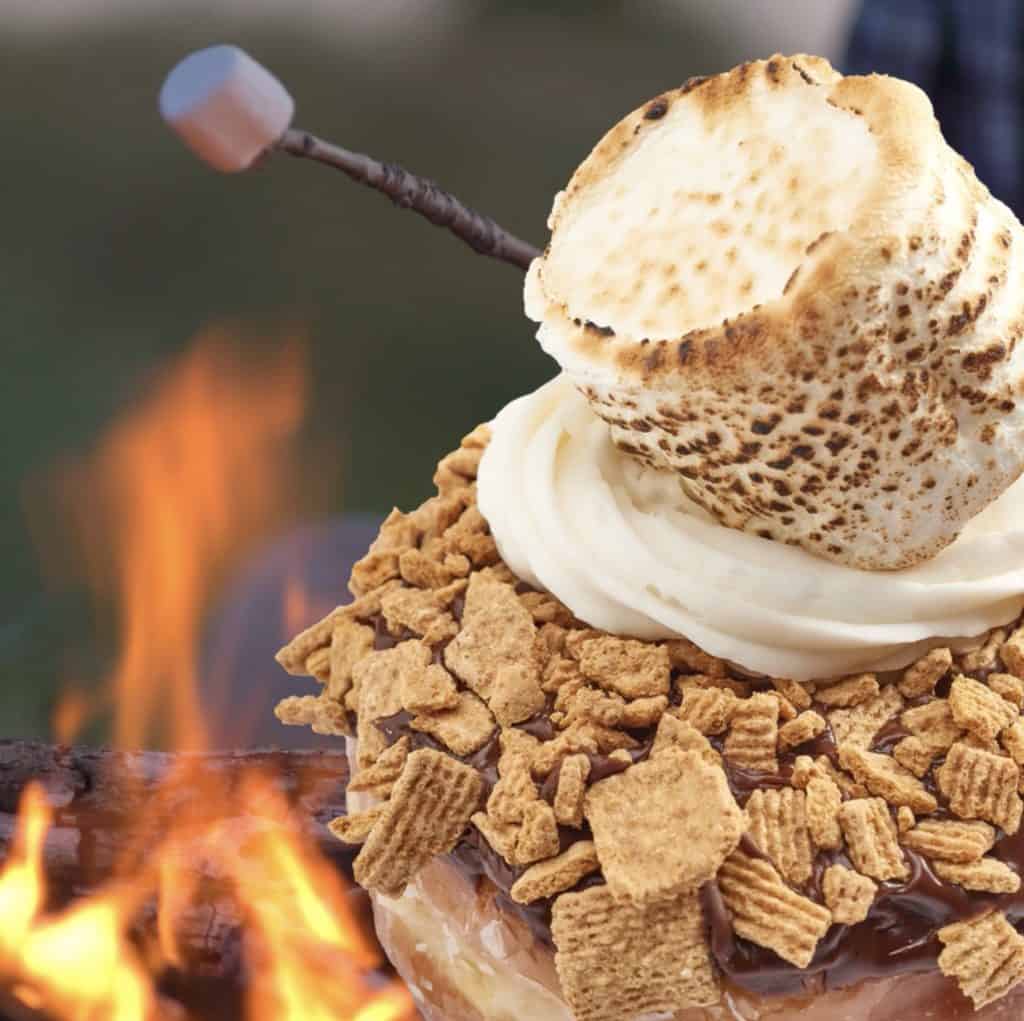 Taste the magic at Disney Springs with the S'mores Galore Donut—this mouthwatering treat is piled high with luscious frosting, crushed graham crackers, decadent chocolate, and crowned with a perfectly toasted marshmallow just like one from a campfire.
