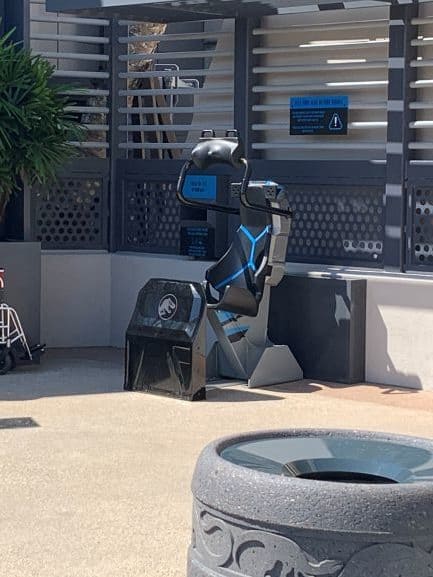 Jurassic Park-themed VelociCoaster test seat on display under a metal canopy at Universal Orlando Resort, inviting thrill-seekers to check out the coaster restraints or snap the perfect pre-ride photo—no crowds in sight.