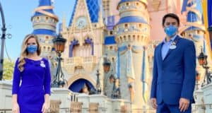 Disney Ambassadors in matching blue suits and face masks pose in front of Sleeping Beauty Castle at Disneyland, showcasing the magic and excitement of the park experience.