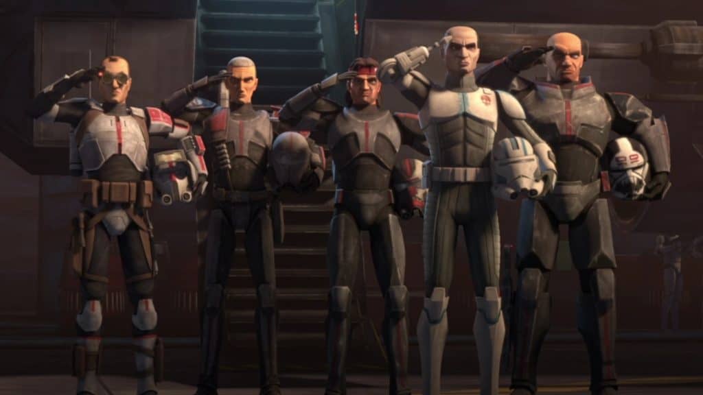 The Bad Batch squad, clad in their signature armor, stand at attention and salute inside a Star Wars-themed attraction on Disney+—their formation set against atmospheric staircases and moody lighting straight from the galaxy far, far away.
