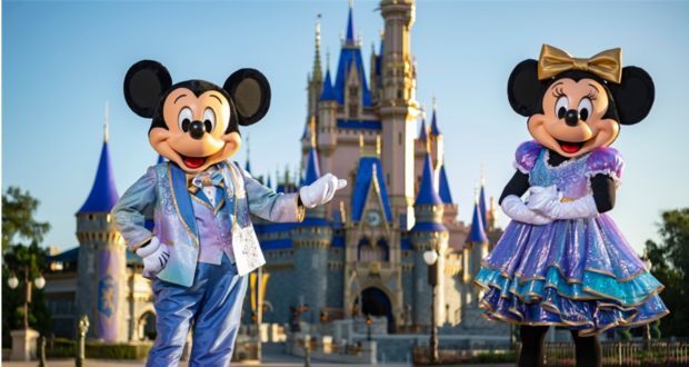Mickey and Minnie Mouse dazzle in vibrant celebration outfits, posing in front of Cinderella Castle at Magic Kingdom to kick off the excitement of Mickey’s Celebration Cavalcade.