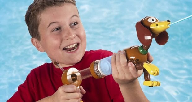 A young guest in a bright red shirt joyfully sprays water from a Slinky Dog Water Blaster at the Toy Story Land pool, delighting in one of the area’s signature water toys.