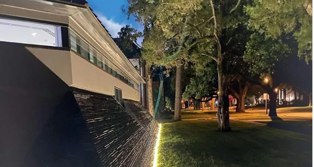 Futuristic house with dramatic angled stone walls lights up the night like a movie set, surrounded by trees and glowing streetlights over lush grass—nicknamed the Darth Vader House, this architectural showstopper could be your own cinematic retreat for $4.3 million.