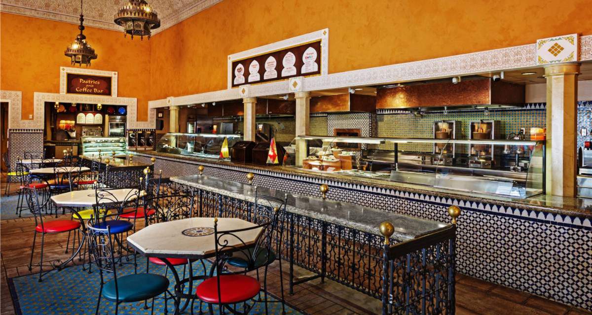 Vibrant café inspired by EPCOT’s Tangierine Café at the Festival Global Marketplace, with colorful chairs, intricate tiled walls, Moroccan-style lamps, and bright orange accents creating an immersive festival vibe.