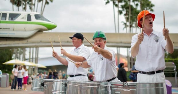 The JAMMitors, dressed in crisp white uniforms and colorful hats, energize EPCOT guests with their lively drum performance as the iconic Disney monorail glides by in the background.