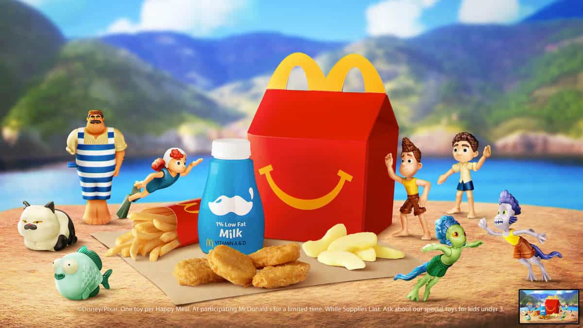 Happy Meal featuring milk, fries, chicken nuggets, and Disney Pixar Luca toys set against a vibrant beach scene reminiscent of an immersive themed attraction.