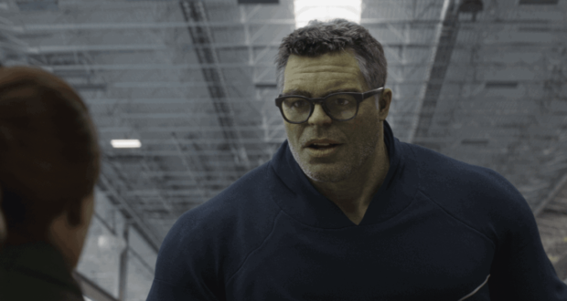 The Hulk, sporting glasses like in the Marvel movies, interacts with a guest inside an Avengers-themed section of a theme park.