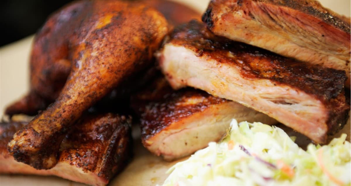 Barbecued chicken and ribs with a side of coleslaw on a plate, served Disney World style for fans craving iconic gluten free dishes from the parks.