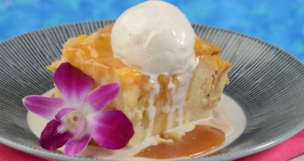 Bread pudding served Disney style at Sebastian’s Bistro in Caribbean Beach Resort, topped with ice cream, a drizzle of caramel sauce, and a vibrant purple orchid—an irresistible treat to mark the reopening celebration.