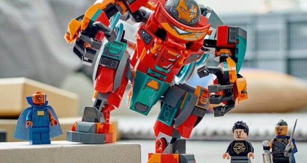 Tony Stark in his Sakaarian Iron Man suit teams up with two other LEGO minifigures beside a vibrant, oversized LEGO mech, ready for action like a hero meet-and-greet at LEGOLAND’s interactive build zone.