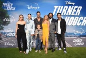 Cast and crew members from "Turner & Hooch" gather in front of the signature Disney+ premiere backdrop, smiling for photos as fans and guests celebrate the series launch.