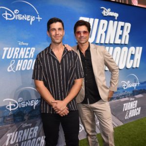 Cast members from Disney+’s "Turner & Hooch" share a cheerful photo moment together at the premiere, standing in front of a branded backdrop celebrating the series launch.