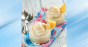 Two glasses of creamy Dole Whip-inspired dessert topped with fresh pineapple, set on a vibrant Disney-themed napkin with spoons at the ready—this classic treat brings the magic of the parks right to your table.