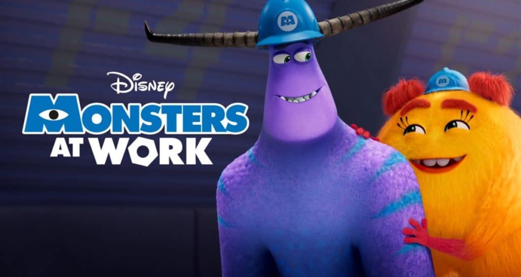 Tylor and Val, two lively monsters in blue hard hats, pose by the vibrant "Monsters at Work" Disney logo, radiating the playful energy guests love from this animated workplace adventure.