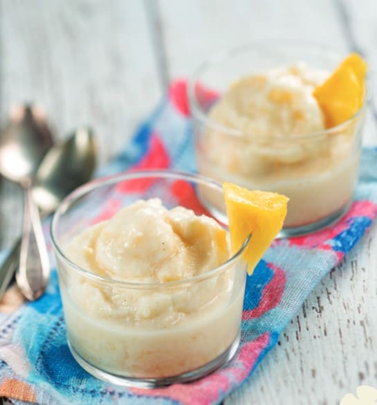 Two glass cups filled with Dole Whip-inspired pineapple dessert, just like the signature treat enjoyed at Disney parks, set on a vibrant cloth with two spoons ready for a magical snack break.
