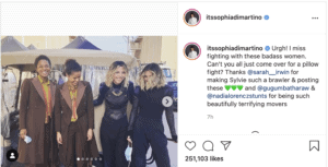 Four women pose together outdoors with big smiles, dressed in stylish black and brown outfits inspired by Loki, arms around each other like they’re part of Sophia Di Martino’s crew at Avengers Campus.