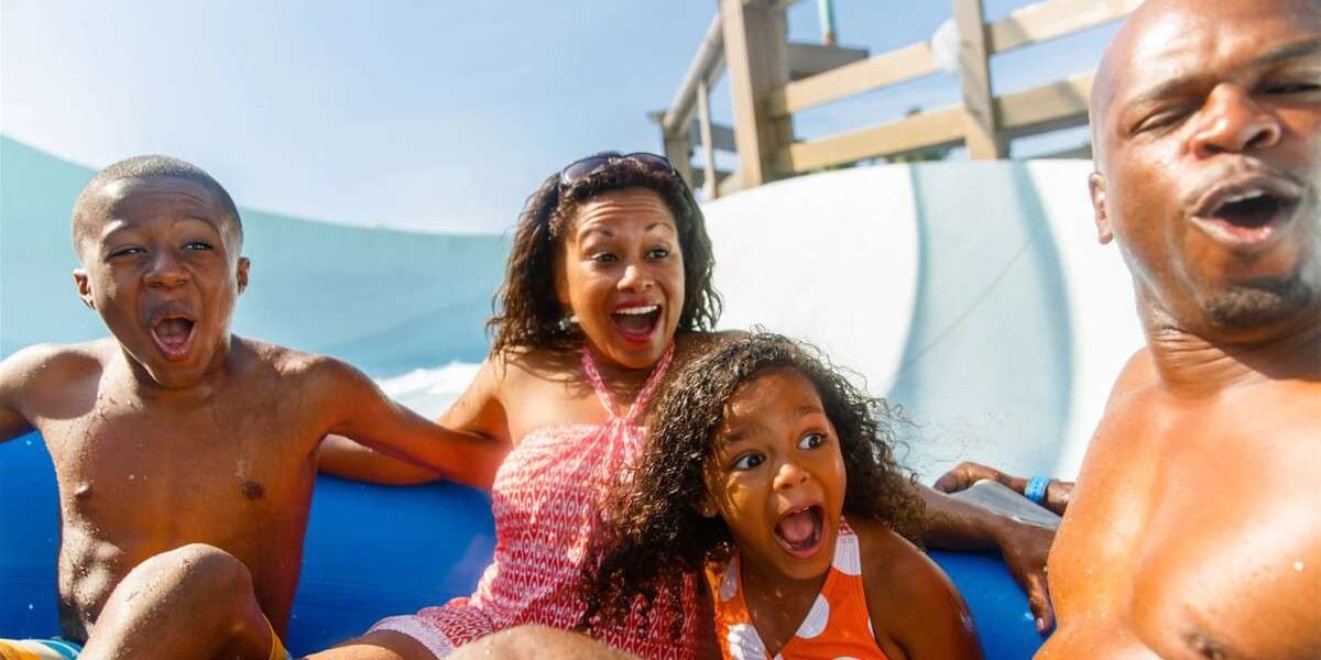Guests experience the thrill of Blizzard Beach as a family of four races down a signature waterslide, each member grinning and laughing with pure Disney excitement.