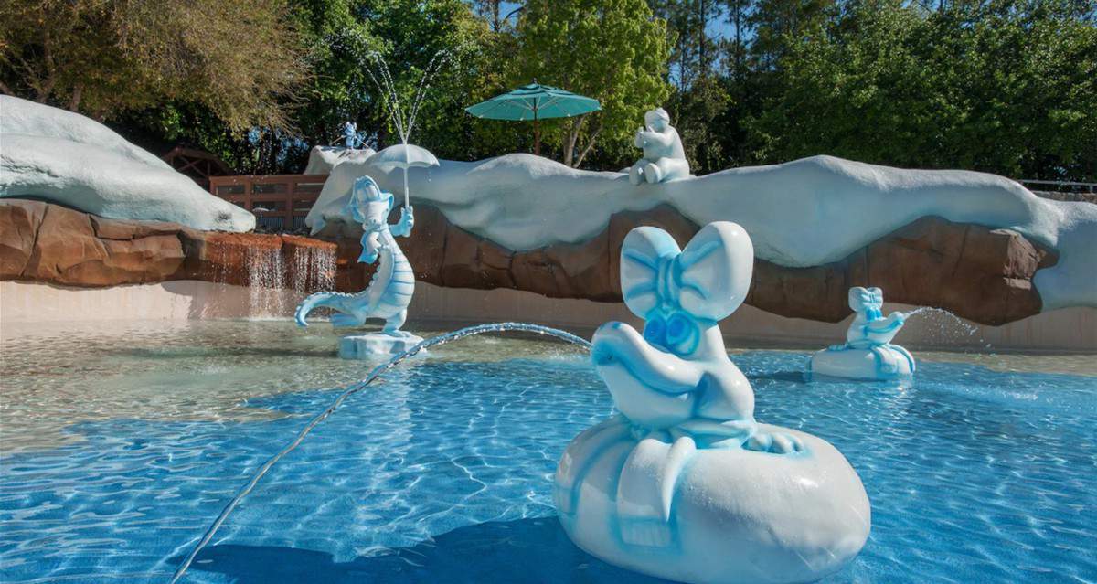 Playful polar bear statues shoot streams of water in a shallow pool amidst trees and rocks, capturing the fun and frosty atmosphere of Disney’s Blizzard Beach Water Park.