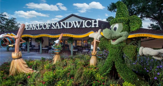 Mickey Mouse topiary greets guests outside the Earl of Sandwich at Disney Springs, surrounded by vibrant greenery and welcoming everyone to try the latest sandwich creation.