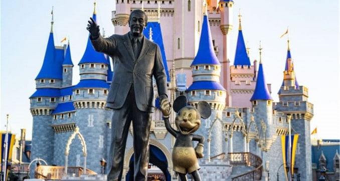 The iconic Partners Statue of Walt Disney holding hands with Mickey Mouse stands proudly in front of Cinderella Castle’s shimmering blue spires at Magic Kingdom.