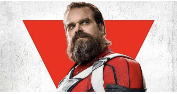 Red Guardian poses in his striking red superhero suit, set against a bold red triangle and crisp white backdrop, ready to greet fans just like at a Marvel theme park experience.