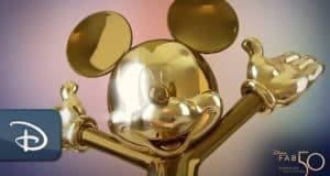 Mickey Mouse gleams in gold with arms raised high, featured as part of Disney World’s “FAB 50” character sculptures. The Disney logo and “FAB 50” text accent the corners, honoring beloved Disney magic for fans and visitors alike.
